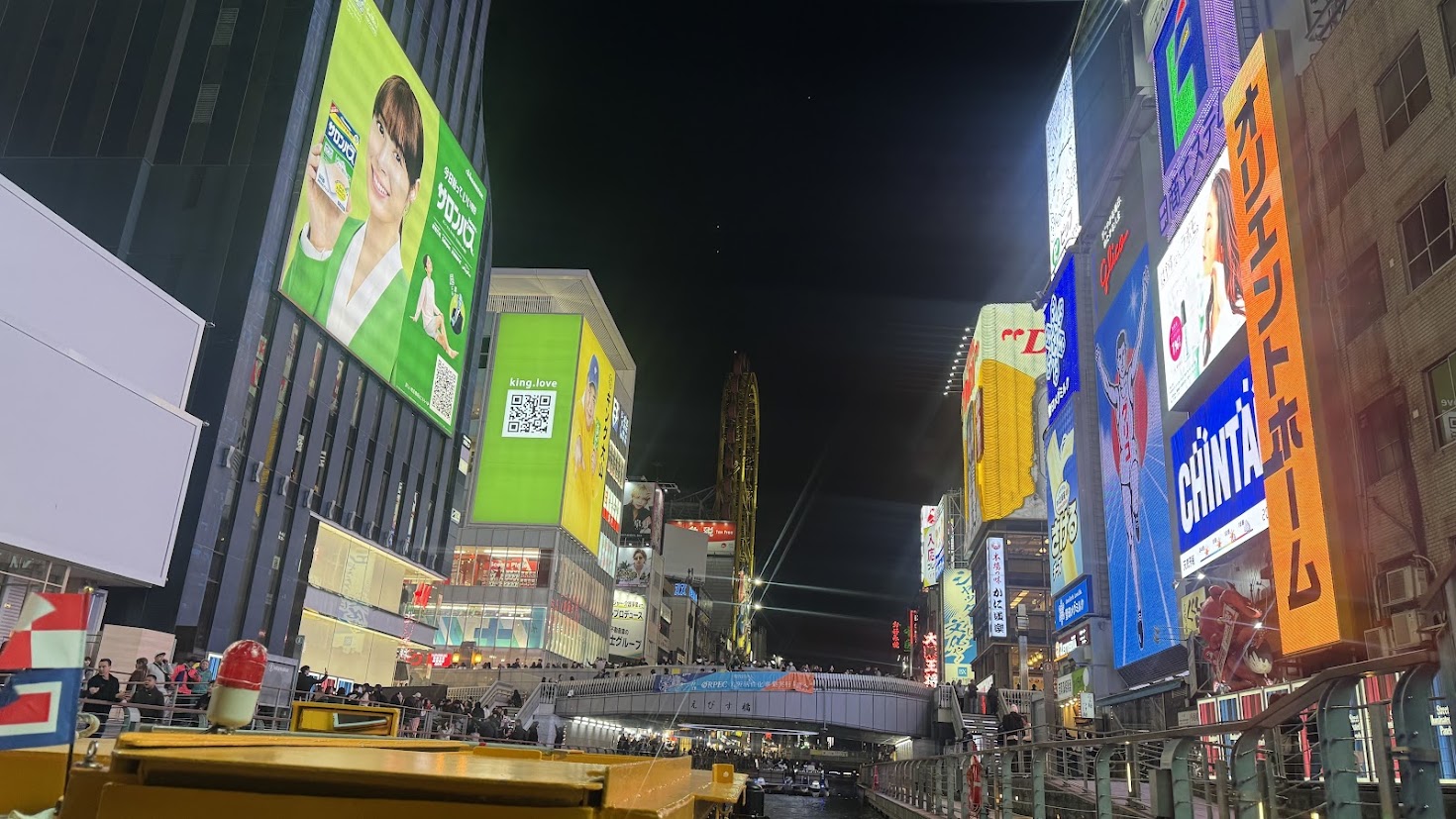 Bright billboards reflected along the Dotonbori canal at night