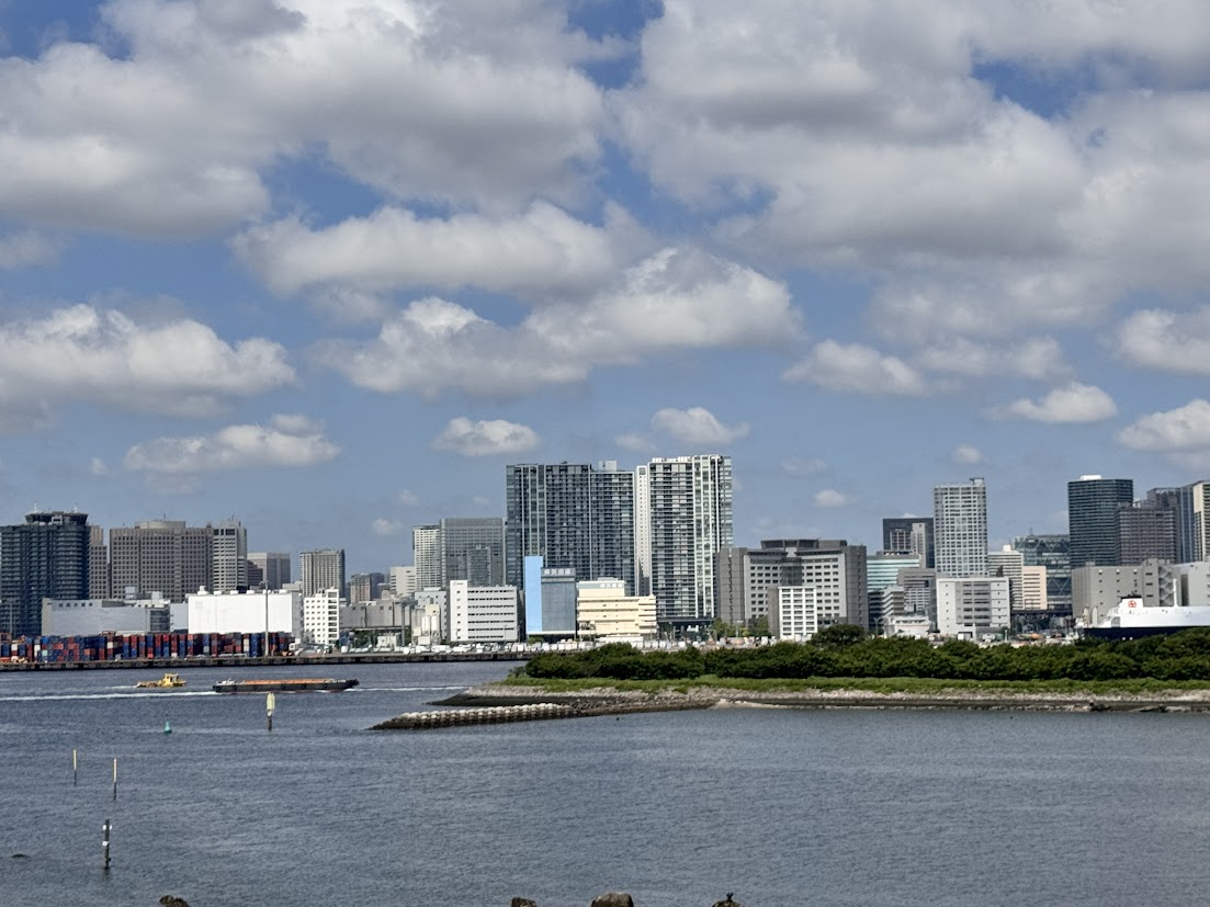 Buildings across the Odaiba waterfront under a cloudy blue sky