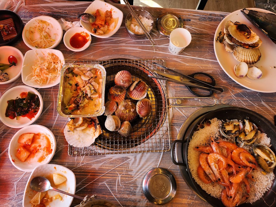Grilled scallops, prawns, and side dishes spread across a restaurant table