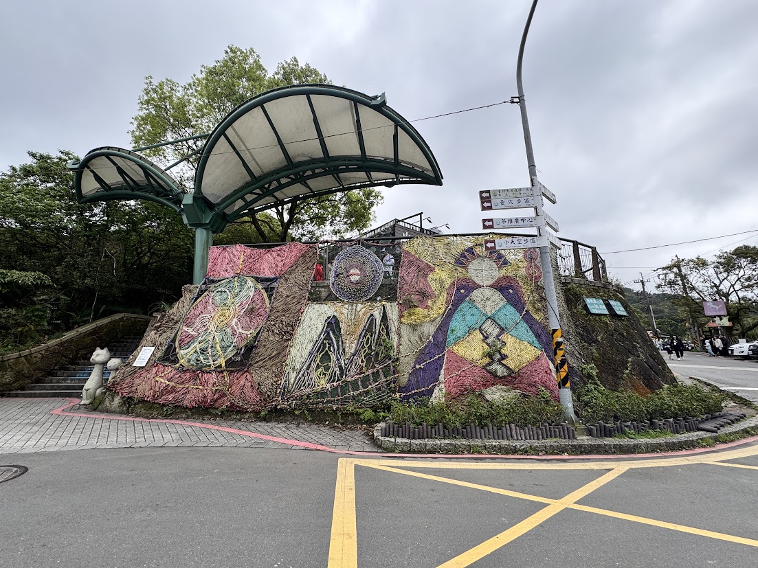 Colorful outdoor artwork beside a covered stairway in Maokong