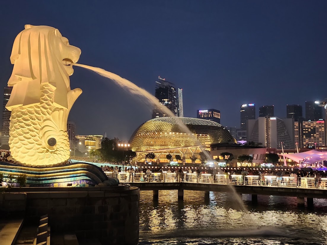 The Merlion lit up beside the Singapore skyline at night