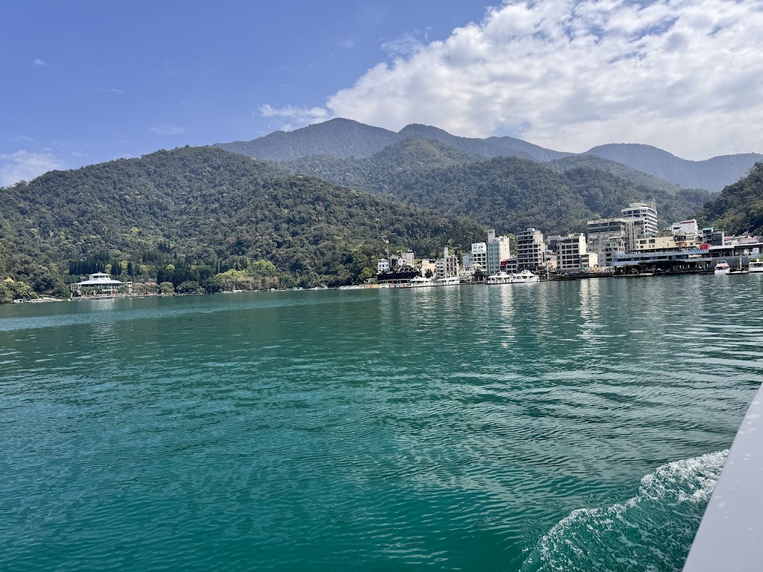 Turquoise lake water facing waterfront buildings and green mountains