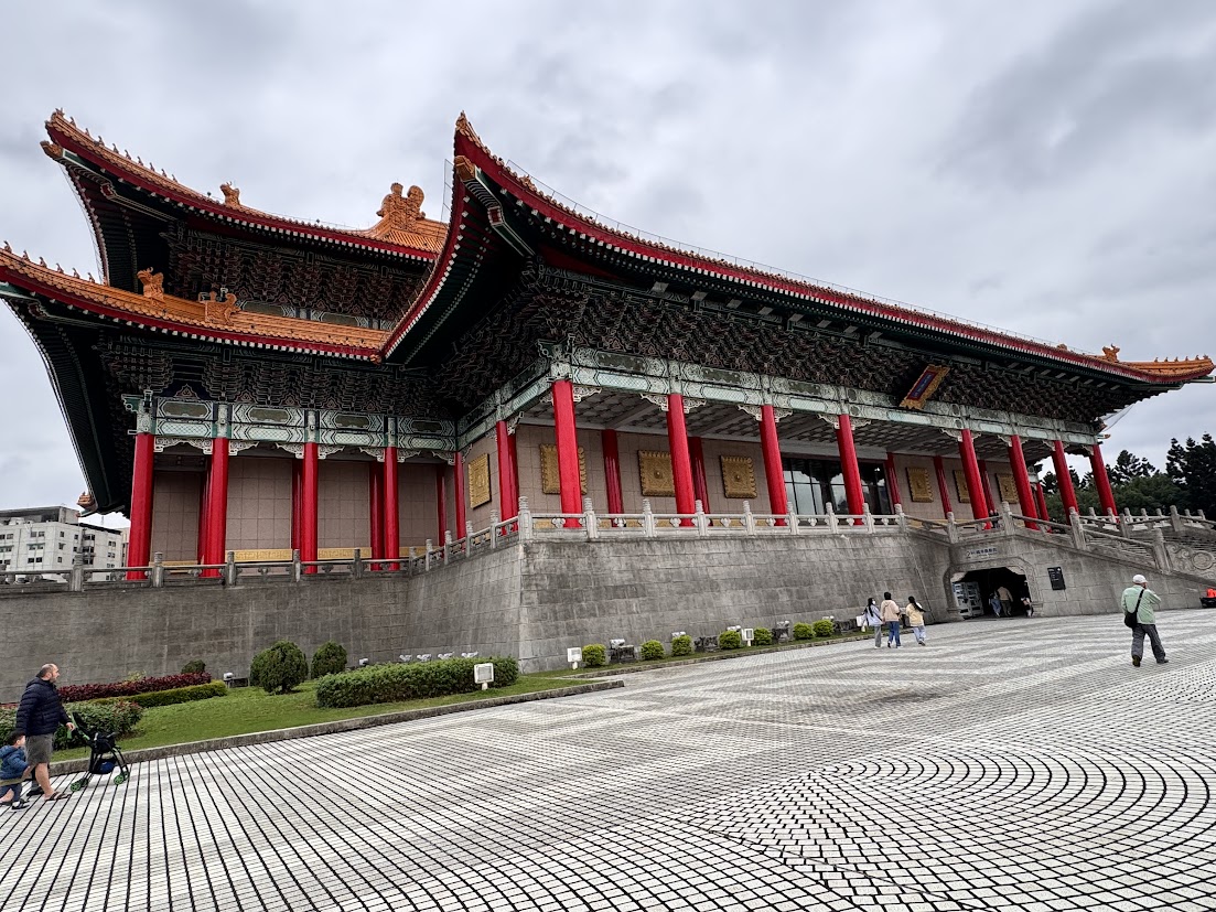 Traditional red columns and ornate tiled roofs beside a broad plaza