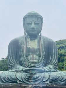 Large seated Buddha statue surrounded by greenery in Japan
