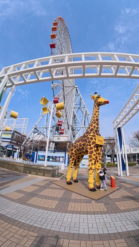Large Ferris wheel near Osaka Bay under a bright blue sky.