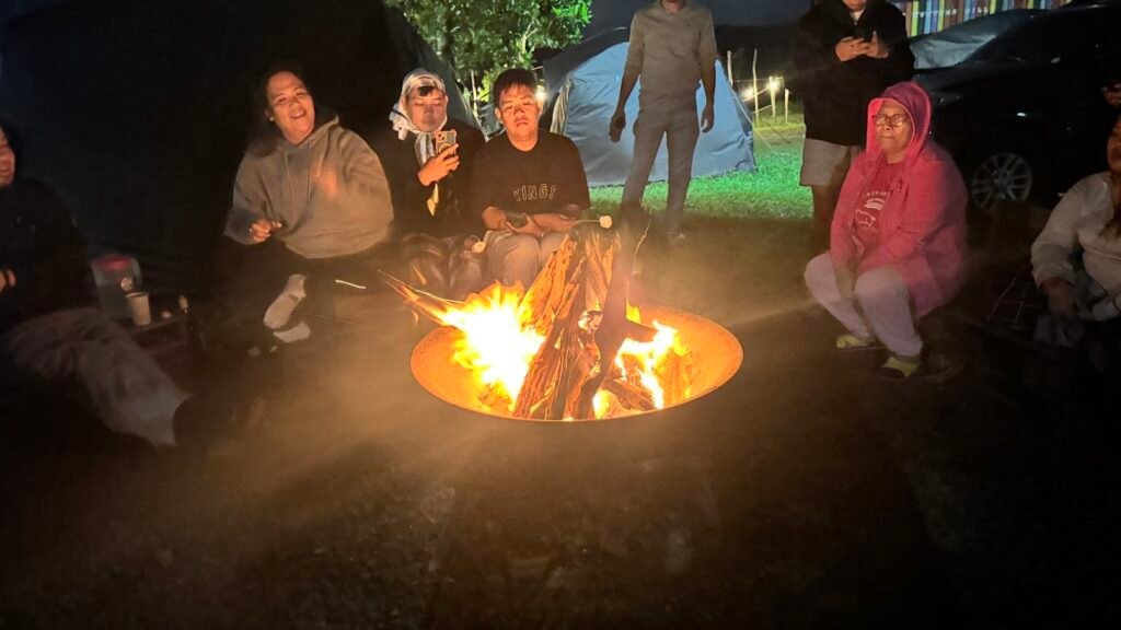 Visitors gathered around a bonfire at night during a camping trip.