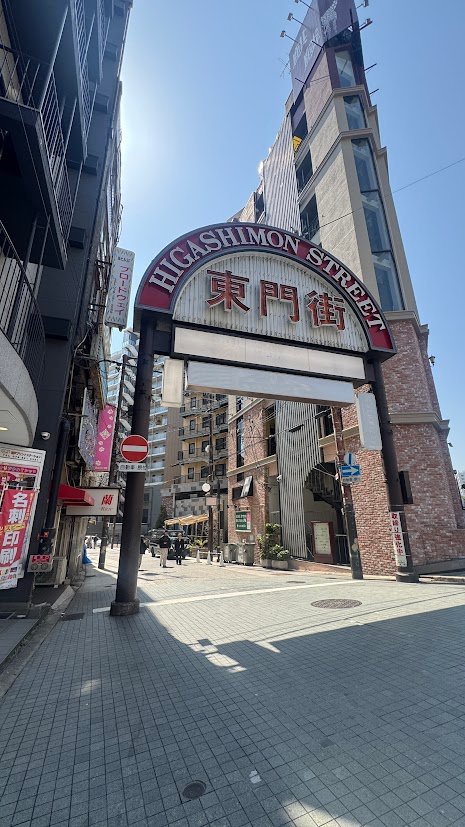 Entrance sign of Higashimon Street in Kobe, Japan surrounded by modern buildings.