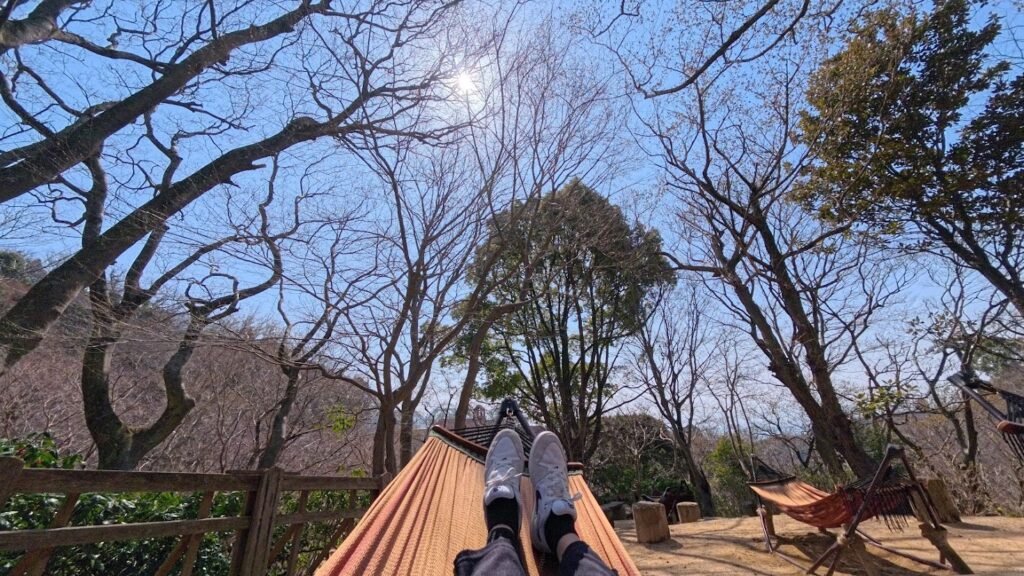 Relaxing on a hammock surrounded by trees at Kobe Nunobiki Herb Gardens in Kobe, Japan.