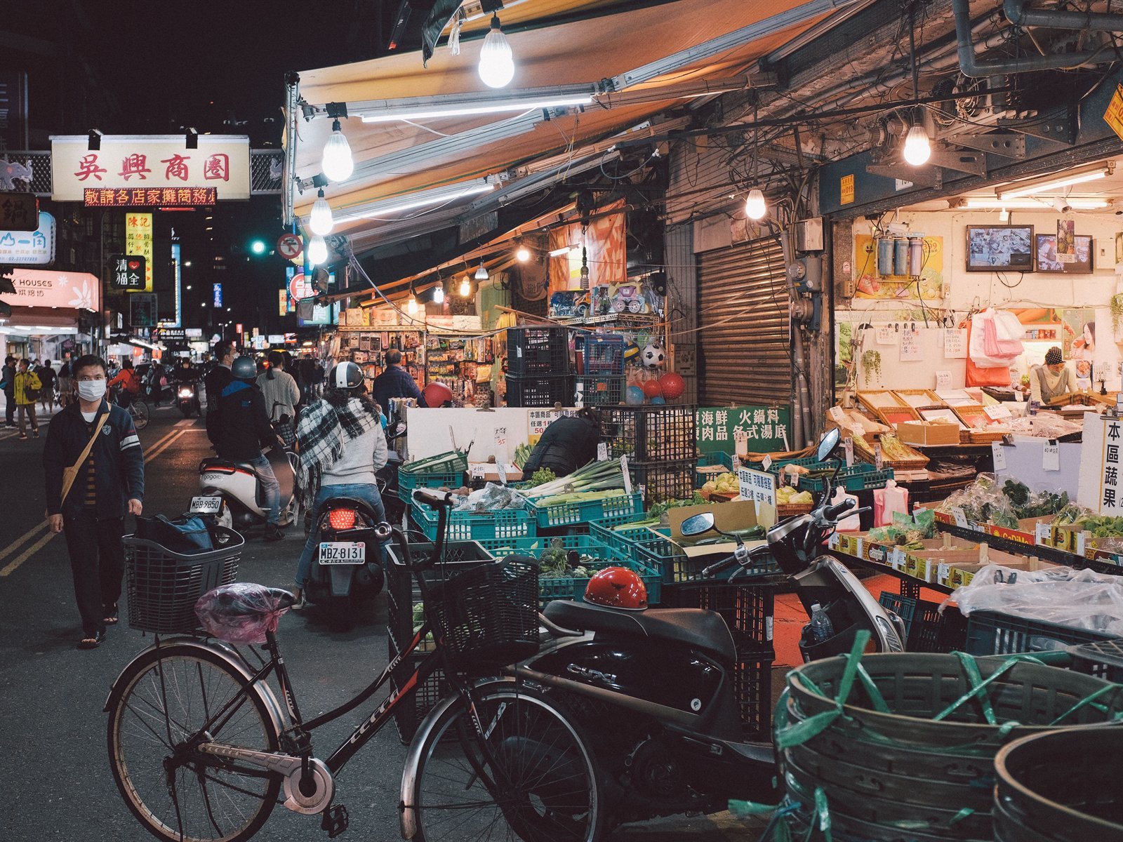 Shoppers and vendors at a Taipei night market after dark